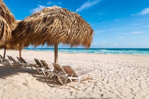 A beach with thatched umbrellas and sun loungers. - Isla Azul Pool & Golf Views, 5 Min to Beach, Near Hard Rock (Punta Cana)