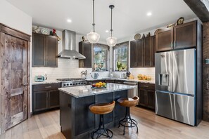 Une cuisine moderne avec des meubles en bois foncé, des appareils électroménagers en acier inoxydable et un îlot central doté de tabourets.
