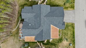 Una casa con techo inclinado, una terraza y un pequeño jardín.