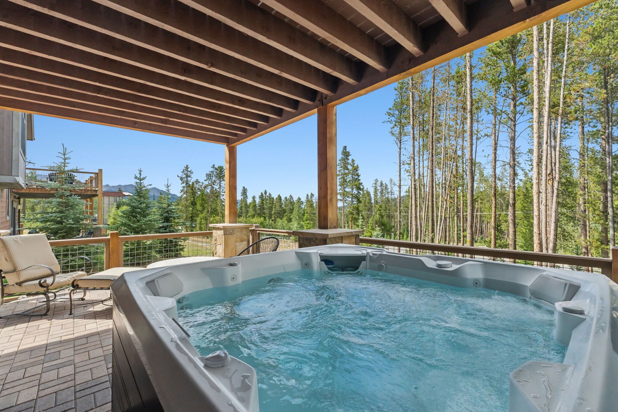 A hot tub on a wooden deck with a view of a forest and mountains.