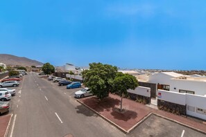 A parking lot with cars, a clear sky, and buildings in the background. - Villa Naira by Villa Plus (Playa Blanca)