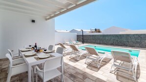 Een terras met een zwembad en lounge stoelen.