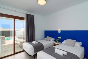 Ein Hotelzimmer mit zwei Betten, einem Balkon mit Pool und einer blauen Akzentwand.