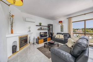A modern living room with a fireplace, a sofa, a coffee table, and a TV. - Villa Casa Mafalda by Villa Plus (Carvoeiro)