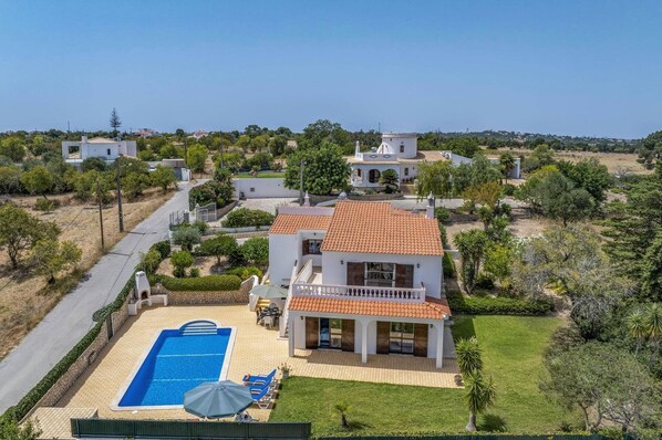 Propiedad residencial con piscina, terraza cubierta y vistas del paisaje circundante.