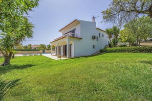 Una casa de un piso con fachada blanca, un balcón y un césped cuidado.