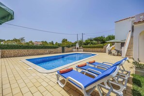 Una piscina con sillones de descanso y un muro de piedra.