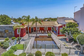 Un complexe hôtelier doté d’une piscine, d’un espace extérieur aménagé et d’un bâtiment rouge.