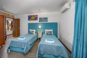 Ein Hotelzimmer mit zwei Betten, einem Nachttisch, einem Fenster mit Vorhängen und Bildern an der Wand.
