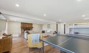 Ein Wohnzimmer mit Tischtennisplatte, einer Couch, einem Couchtisch und einem Kamin.