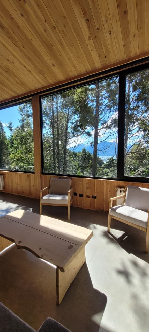 A room with large windows, wooden ceiling, and two chairs.