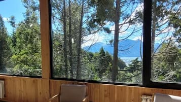 A room with large windows, wooden ceiling, and two chairs.