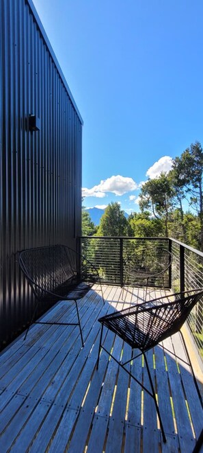 A wooden deck with metal railings and a black metal chair. - Hestia en Dachas Patagonia (San Carlos de Bariloche)