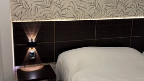 A bedroom with a bed, a nightstand, and a wall with a leaf pattern. - Hotel Aquarium (Punta del Este)