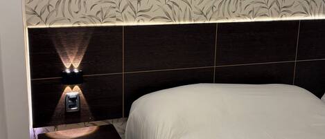 Un dormitorio con una cama, una mesita de noche y una pared con un diseño de hojas.