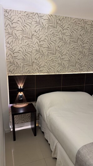 A bedroom with a bed, a nightstand, and a wall with a leaf pattern. - Hotel Aquarium (Punta del Este)