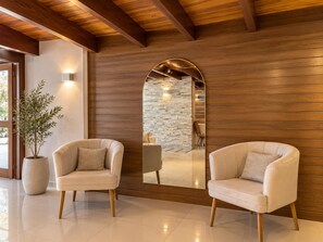 A modern interior with two leather armchairs, a large mirror, and a potted plant.