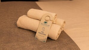 A neatly folded towel with a tag on a bed. - Hotel Aquarium (Punta del Este)
