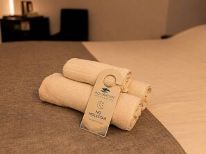 A neatly folded towel with a tag on a bed. - Hotel Aquarium (Punta del Este)