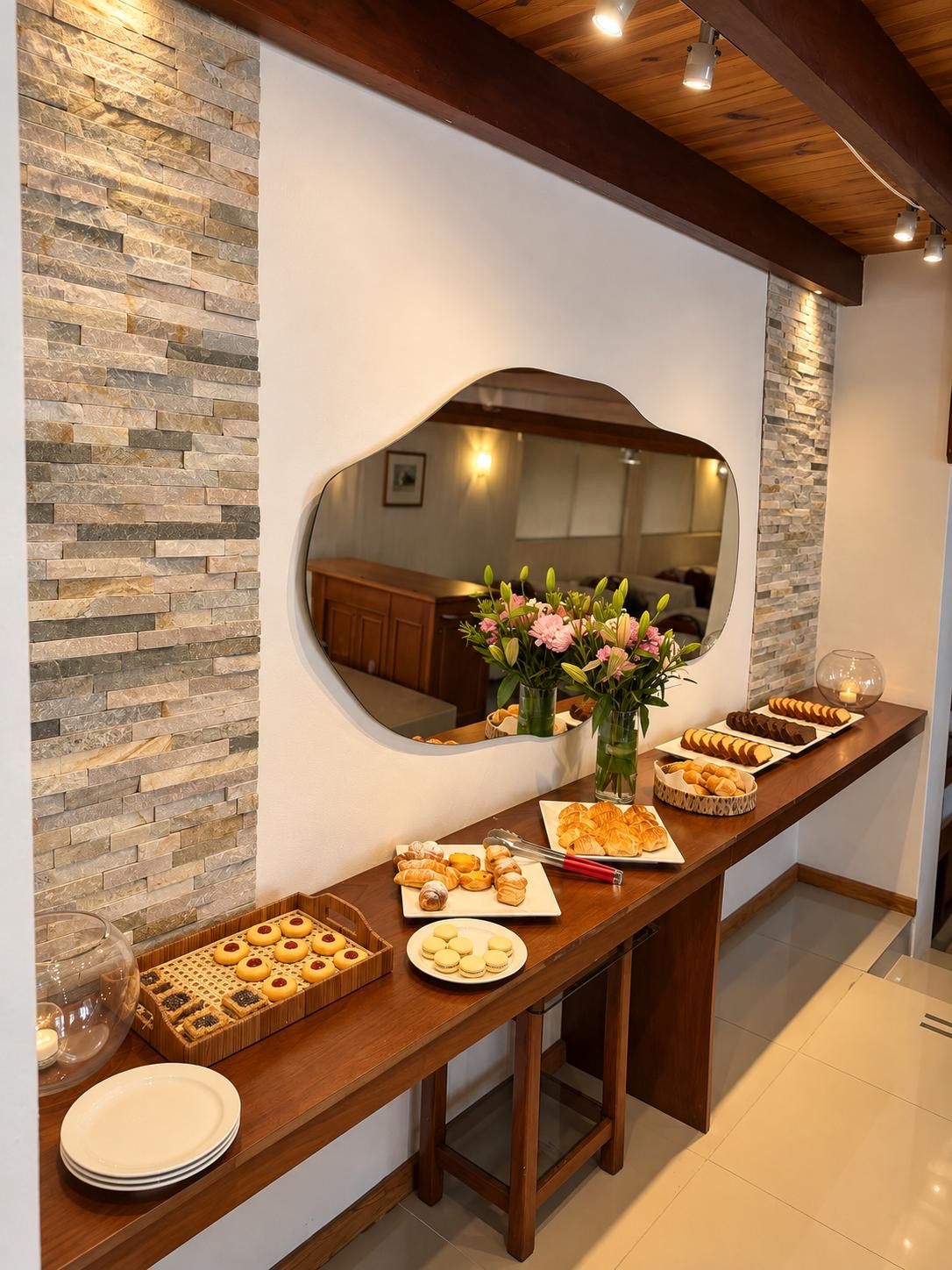 Une table de buffet garnie de diverses pâtisseries et un miroir qui reflète la pièce.