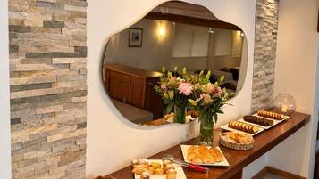 Une table de buffet garnie de diverses pâtisseries et un miroir qui reflète la pièce.
