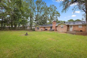 A residential property with a grassy yard, a brick house, and a chimney.