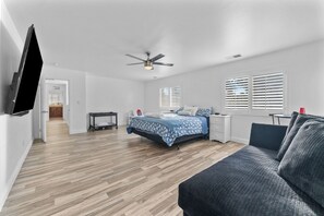 A modern bedroom with a bed, a desk, a chair, and a ceiling fan. - Lovely 5-bedroom 3 Full Bathroom House In Charming Southwest Bakersfield (Bakersfield)