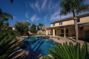 A swimming pool surrounded by palm trees and a two-story building with a flat roof. - Lovely 5-bedroom 3 Full Bathroom House In Charming Southwest Bakersfield (Bakersfield)