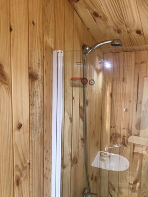 A wooden interior with a shower enclosure, a visible water control valve, and a white fixture. - Esparza lodge (Los Lagos)