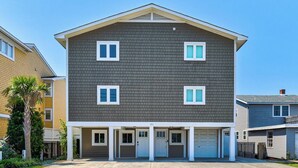 Edifício residencial de dois andares com fachada cinza escura, detalhes em branco e várias janelas.