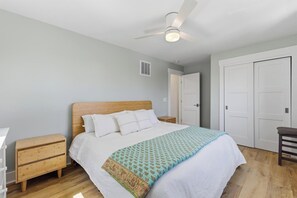 A bedroom with a bed, wooden nightstands, a ceiling fan, and a wardrobe.