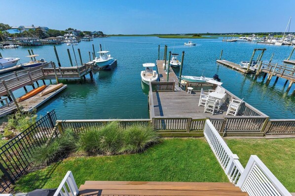 A marina with boats docked, wooden walkways, and grassy areas.