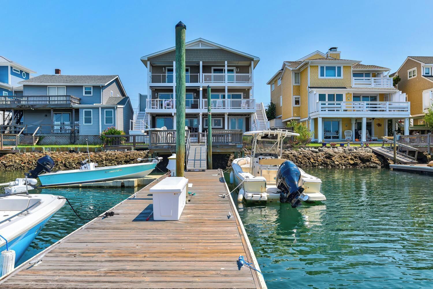 Un puerto deportivo con un muelle de madera, barcos y edificios residenciales de varios pisos con balcones.