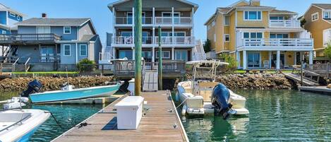 A marina with a wooden dock, boats, and multi-story residential buildings with balconies.