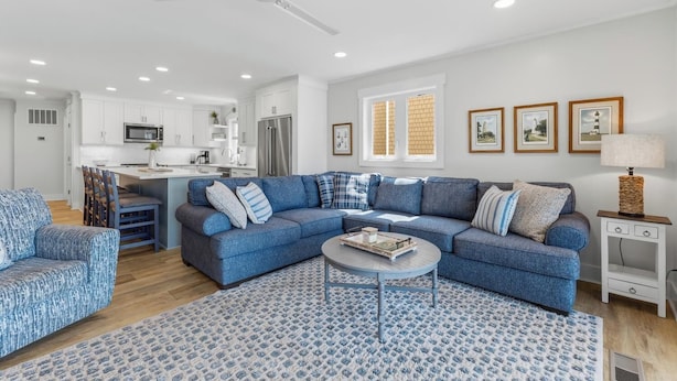 Uma sala de estar moderna com sofá azul, mesa de centro e área de jantar com cadeiras.