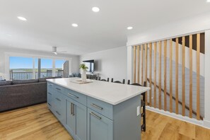 Una cucina moderna con una grande isola, mobili grigi e vista all'esterno.
