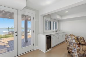 A modern kitchen with a view of the water, a built-in dishwasher, and a patterned sofa.