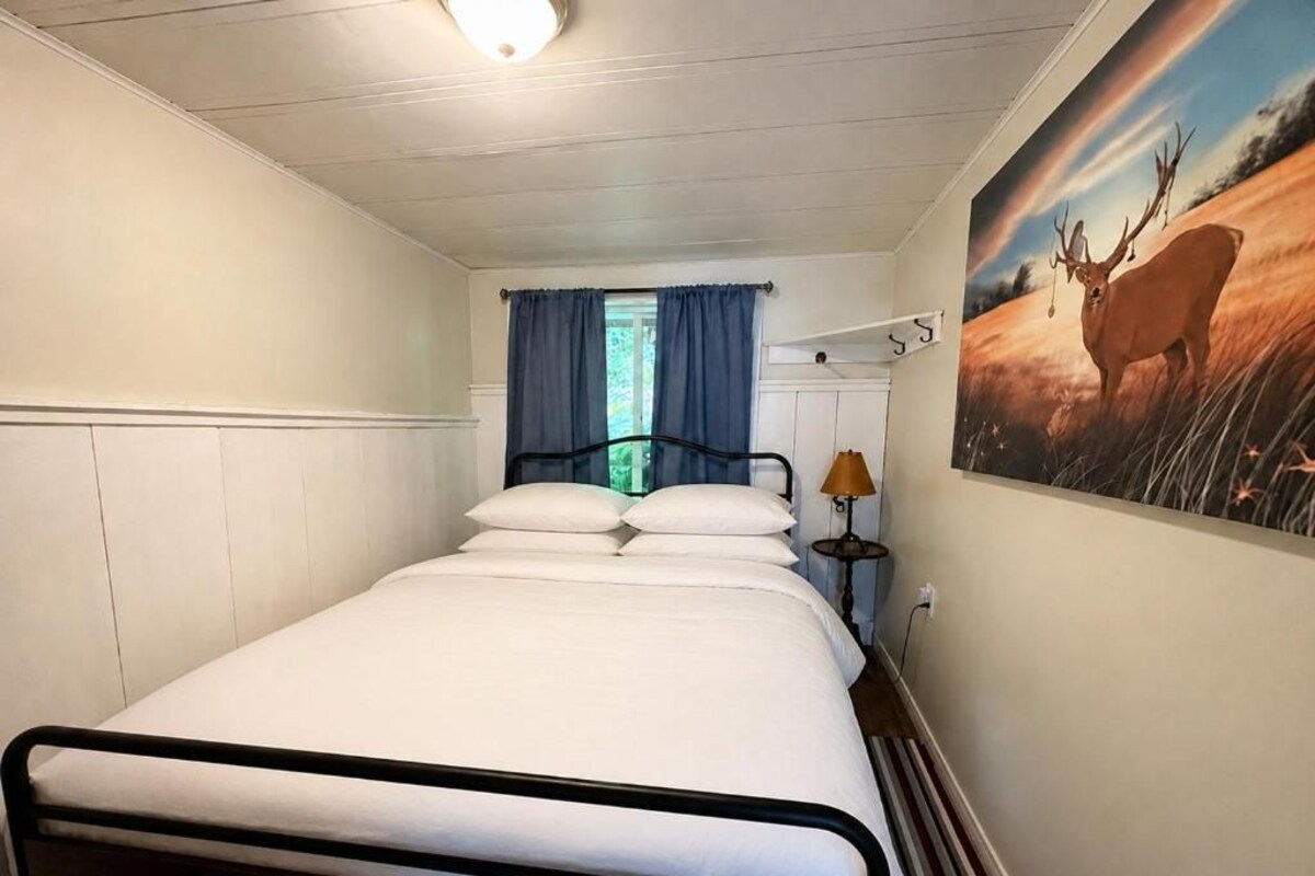Un lit simple avec un cadre en métal, une table de chevet avec une lampe et une étagère fixée au mur.