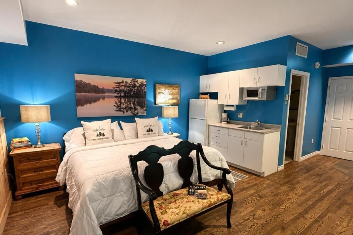 Une chambre à coucher avec un lit, une table de chevet, une lampe et un banc.
