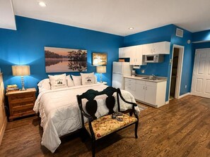 Une chambre à coucher avec un lit, une table de chevet, une lampe et un banc.