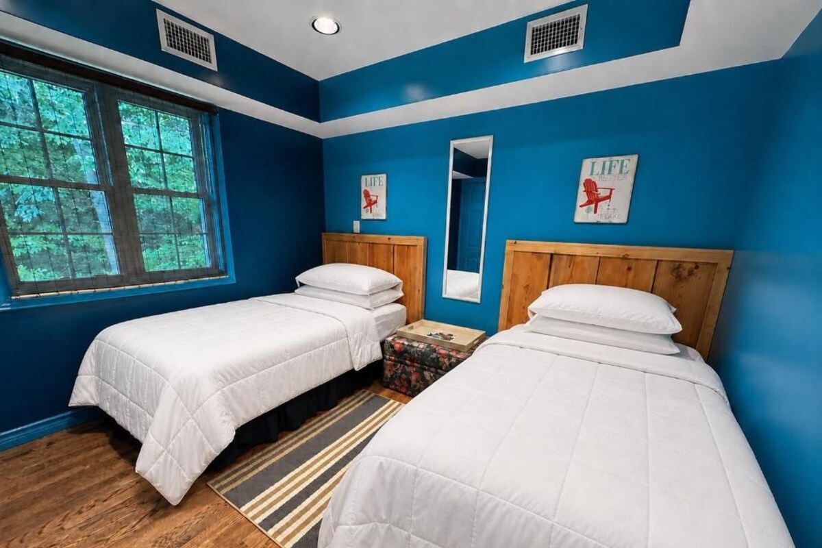 Une chambre avec deux lits, une fenêtre et un miroir.