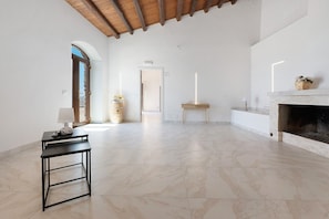 A spacious room with a marble floor, a fireplace, a table with a lamp, and a door leading to another area. - A Briogna Room - Sikania Agrirelais, Mountain View (Caccamo)