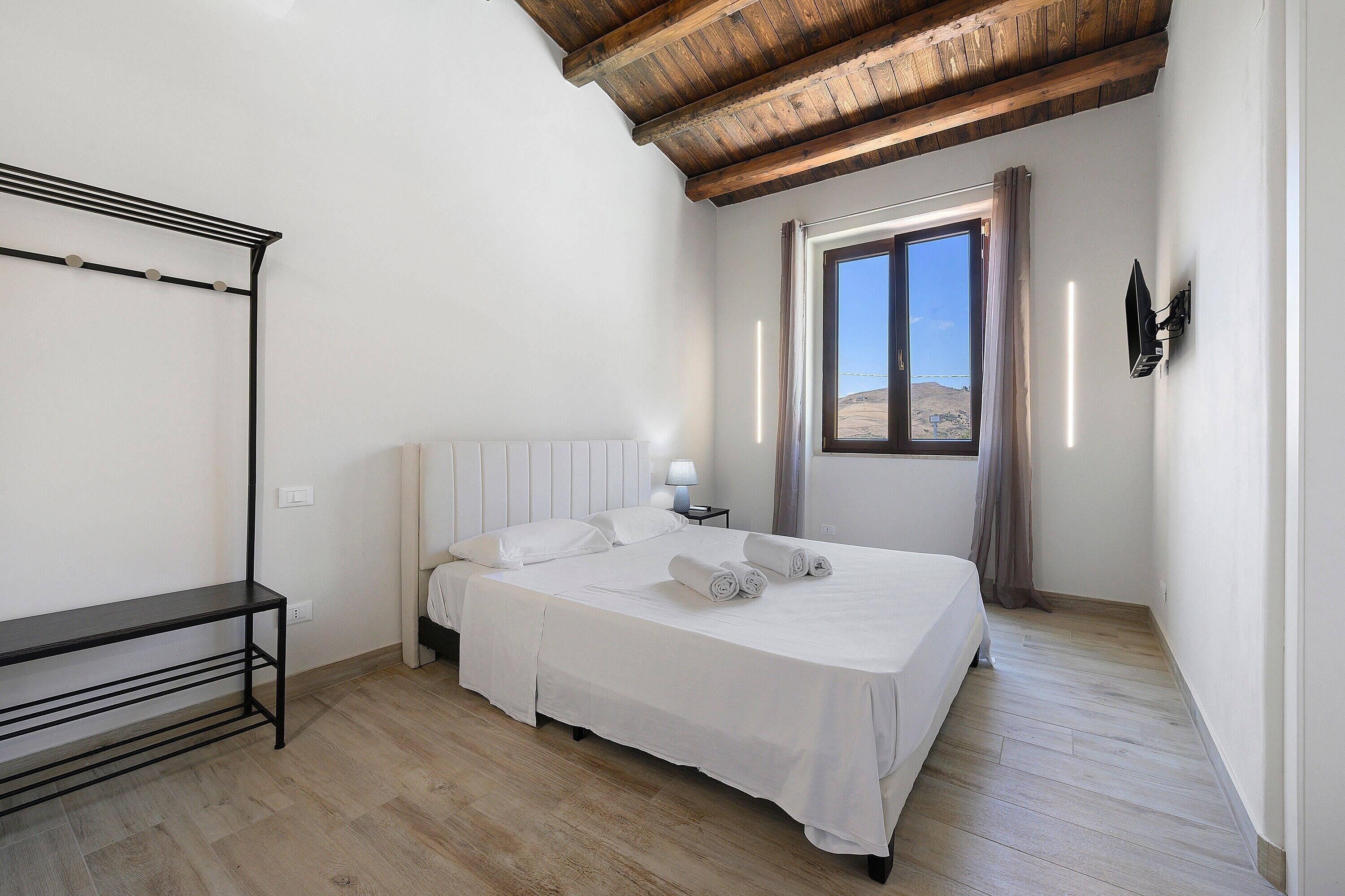Una camera da letto con un letto, un comodino, una lampada, una finestra e un soffitto in legno.