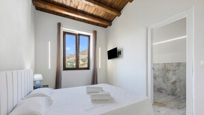 Una camera da letto con un letto, un comodino, una TV a parete e una finestra con tende.