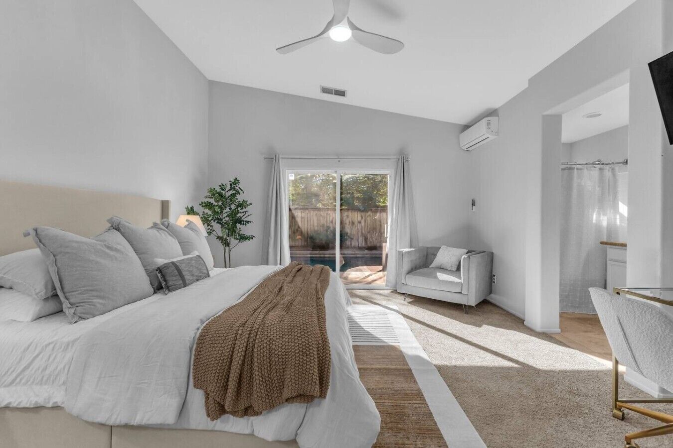 Une chambre à coucher avec un lit, une table de chevet, une chaise et une vue sur l’extérieur.