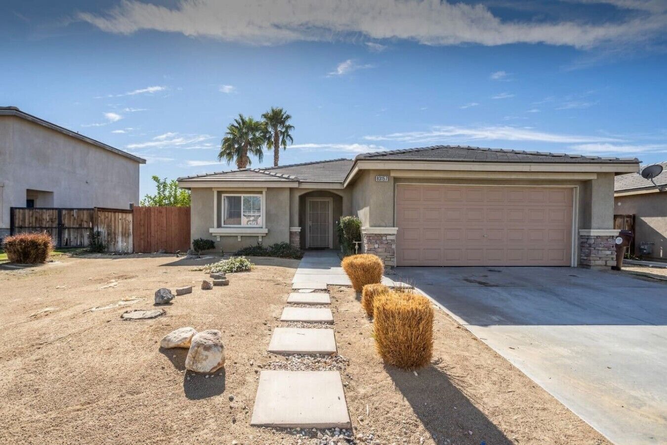 A residential property with a paved driveway, a garage, and a well-maintained front yard with landscaping.