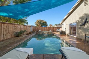 A backyard with a swimming pool, a wooden fence, and a patio area with lounge chairs. - Early Check-In. AC Comfort + Pool, Spa +FAST WIFI (Coachella)