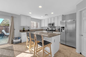 A modern kitchen with white cabinets, a stainless steel refrigerator, and a granite countertop. - Early Check-In. AC Comfort + Pool, Spa +FAST WIFI (Coachella)