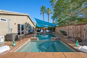 Un patio trasero con piscina, mobiliario exterior y una valla de madera.