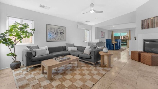 En moderne stue med en grå sofa, et sofabord og en stor plante.